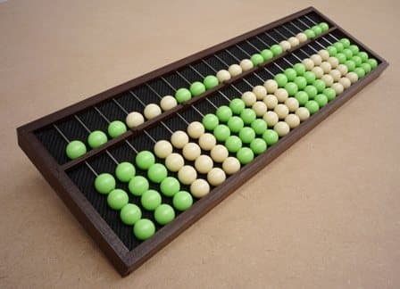 Ábaco de madera con cuentas verdes y blancas dispuestas en varias columnas.