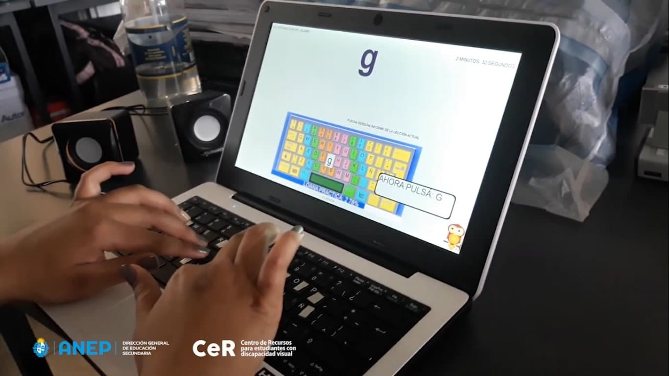 Estudiante escribiendo en el teclado de una computadora portátil que muestra un ejercicio de mecanografía con la letra G.